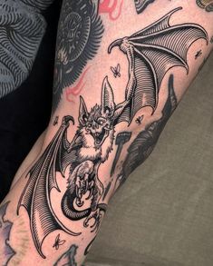 a man's arm with a bat tattoo on it, and an image of a demon