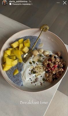 a bowl with granola, yogurt and fruit on it next to a spoon