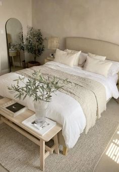 a bedroom with a bed, mirror and plant on the table in front of it