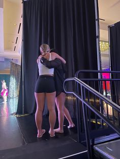 two women in short shorts standing on stage with their arms around each other's shoulders