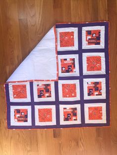 an orange and purple quilt is laying on the floor