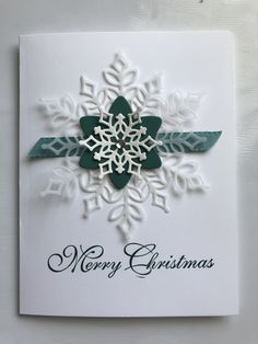 a christmas card with a snowflake on the front and green ribbon around it