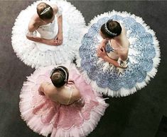 three ballerinas in tutu skirts are looking down at their heads and shoulders