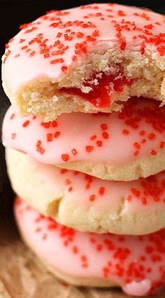 three cookies with pink icing and red sprinkles are stacked on top of each other