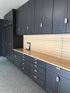 an empty kitchen with black cabinets and wood counter tops in the middle of the room