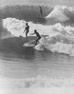 black and white photo of surfers riding waves in the ocean