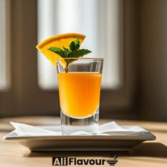 a glass filled with orange juice sitting on top of a table next to a slice of lemon