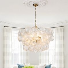 a living room filled with furniture and a chandelier hanging over the couches