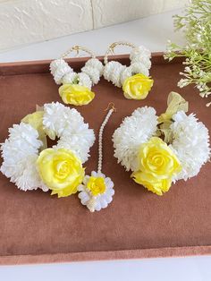 yellow and white flowers are on display in a box next to other items that include necklaces, earrings and bracelets