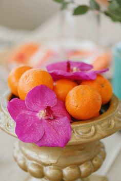 a bowl filled with oranges and pink flowers