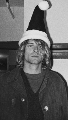 a man wearing a santa hat standing next to a wall