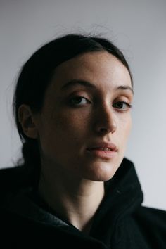 a woman in a black jacket looking at the camera with a serious look on her face