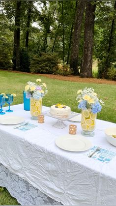 a table set up with plates, cups and vases filled with flowers on it