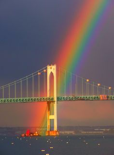 a rainbow is shining in the sky over a bridge