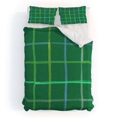 a green and blue plaid comforter set on a white bed with two pillow cases