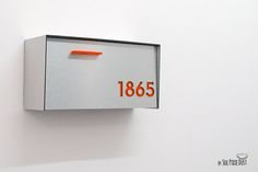 a close up of a mailbox on a wall with an orange light at the top