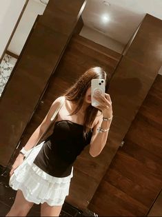 a woman taking a selfie in front of a mirror wearing a black and white dress