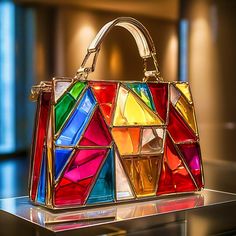 "Radiant Spectrum" is a digital artwork that showcases a handbag adorned with a dynamic mosaic of stained glass panels. The vibrant reds, blues, greens, yellows, and oranges are expertly arranged to create a harmonious yet striking composition. The polished brass framework adds a touch of elegance, while the structured handle completes the design. This piece captures the essence of a radiant spectrum, reflecting light in a mesmerizing array of colors. Tiffany Lamp, Reflecting Light, Stained Glass Panels, Stain Glass, Pocket Book, Product Photos, Glass Panels, Polished Brass, Vibrant Red