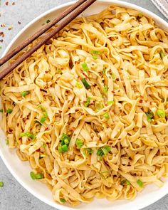 a white bowl filled with noodles and chopsticks