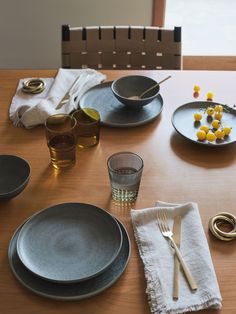 a wooden table topped with plates and bowls