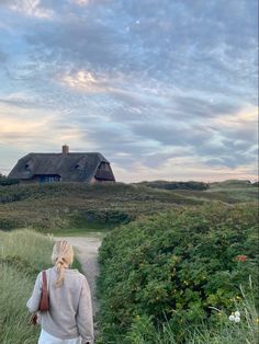 a woman walking down a path towards a house