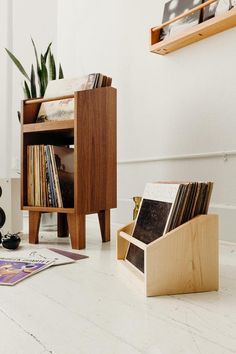 a record player sitting on top of a white floor next to a wooden box filled with records