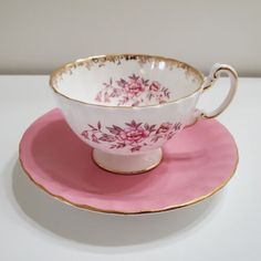 a pink and gold tea cup on a saucer