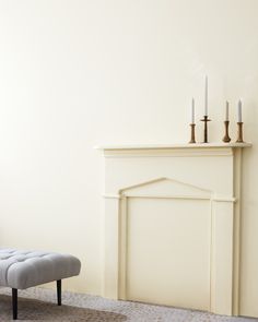 a living room with a white fireplace and two candles on top of the mantel