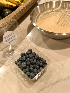 blueberries and bananas are in bowls on the counter next to other foodstuffs