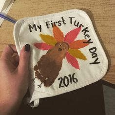 a person is holding up a turkey pot holder with the words my first turkey day on it