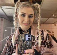 a girl with braids holding up her cell phone