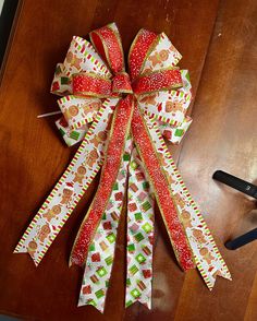 a pair of scissors sitting on top of a wooden table next to a christmas bow