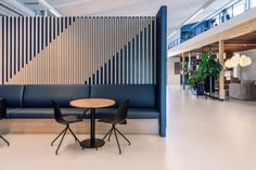 an office lobby with blue and white walls, black chairs and a round wooden table