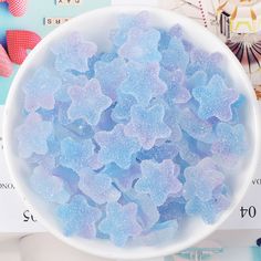 a white bowl filled with blue candy flakes on top of a table next to other items