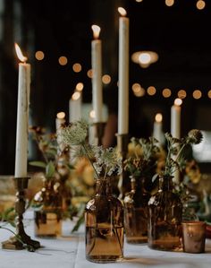 several vases with flowers and candles on a table