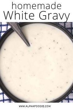 a bowl of homemade white gravy with a spoon in it on a blue and white checkered cloth