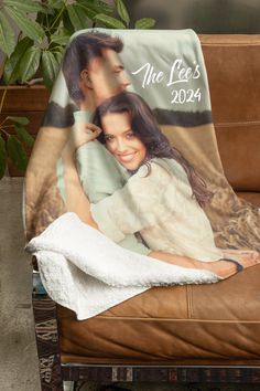 a personalized photo on a blanket is sitting on a leather chair next to a potted plant