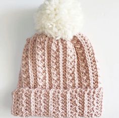 a pink knitted hat with a white pom - pom