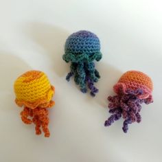 three crocheted jellyfish sitting next to each other on a white table top