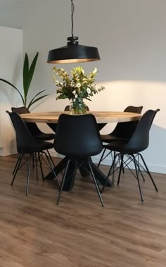 a dining room table with chairs and a vase on it's centerpiece in front of a white wall