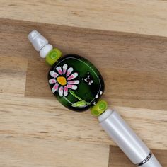 a green and white flowered bottle stopper on a wooden table with wood grain