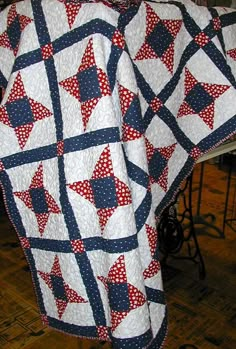 a red, white and blue quilt with stars on it sitting on top of a table