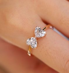 a woman's hand with two engagement rings on her left and the ring has three pear shaped diamonds in it