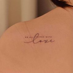 the back of a woman's shoulder with a tattoo saying do all things with love