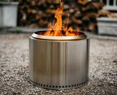 a metal fire pit sitting on top of a gravel covered ground