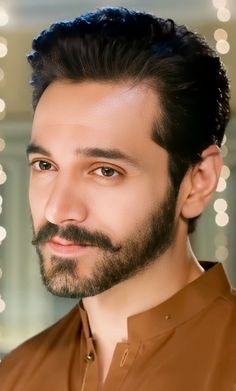 a close up of a person wearing a brown shirt and beard with lights in the background