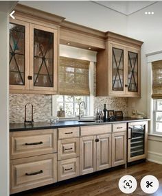 a kitchen with wooden cabinets and black counter tops in front of a window that has roman shades on the windowsills