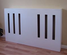 a white radiator sitting on top of a hard wood floor next to a wall