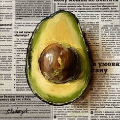 an avocado cut in half sitting on top of a newspaper