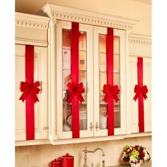 two red bows are tied on the back of white china cabinets